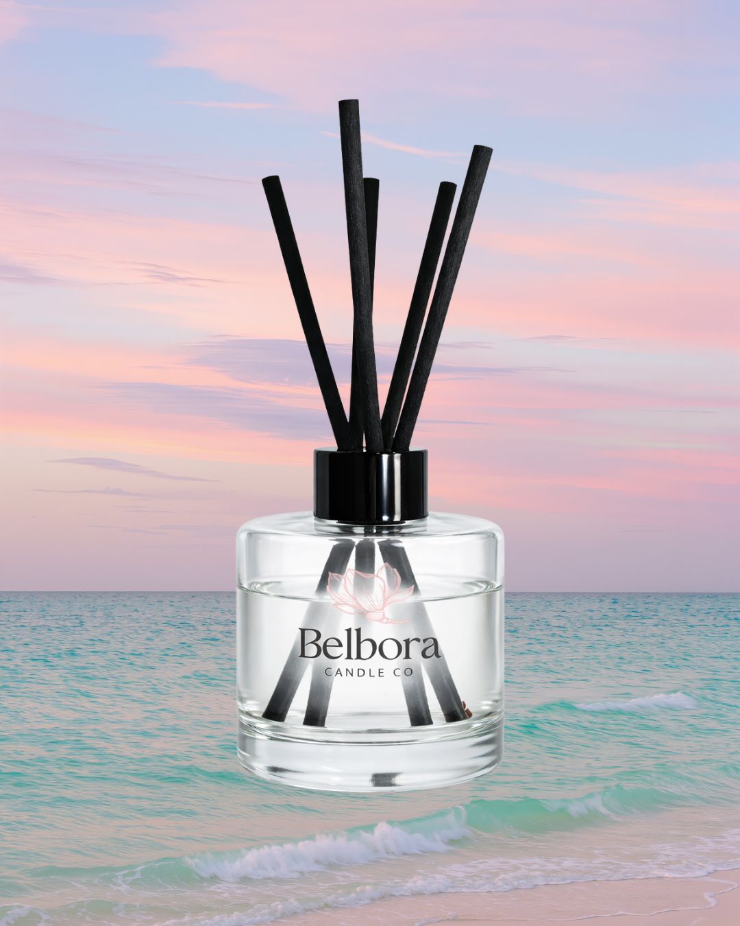 Belbora Candle Co Heading to the coast reed diffuser with black sticks against a beach sunset background