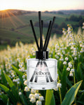 Belbora diffuser bottle with black sticks in a field of white flowers during sunset.